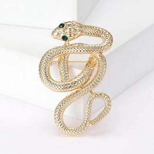 Vintage gold snake brooch with green gemstone eyes and textured metal scales on white