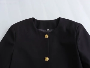 Close-up of black round neck jacket featuring exquisite gold embossed buttons on front