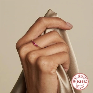 Detail of 925 sterling silver gold ring with red zircon stone on satin fabric