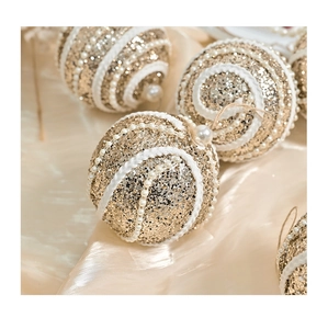 Detail of golden Christmas ball with white sequins and pearls on silk background