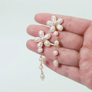 Detail of handmade natural freshwater pearl flower earrings with long gold tassels
