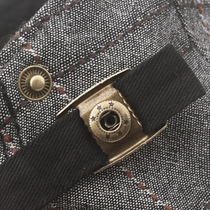 Detail of plaid cotton newsboy hat showing copper star snap button and elastic band