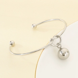 Detailed shot of silver hollow ball charm on a polished stainless steel open bangle