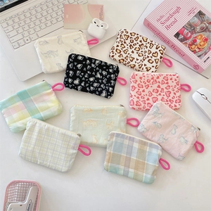 Flat lay of multiple floral and leopard print canvas coin purses on a white desk
