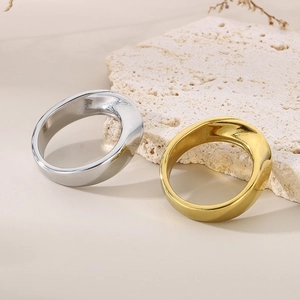 Irregular stainless steel rings in gold and silver finish on a natural stone background