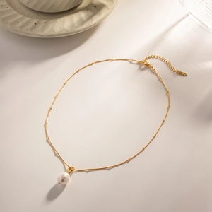 Detail of gold K18 necklace chain featuring tiny beads and a white round pearl pendant