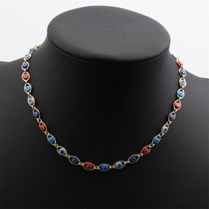Détail du collier œil maléfique plaqué or sur un présentoir avec finitions en émail coloré