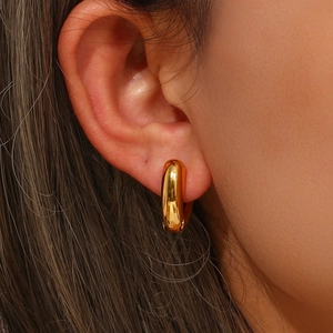 Close-up of high-polish golden hoop earrings on model featuring a minimalist style