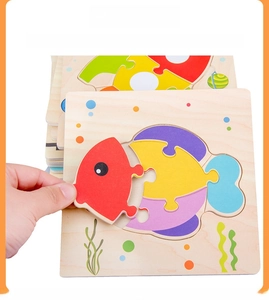 Detail of wooden fish puzzle showing hand grasping colorful pieces for motor skill training