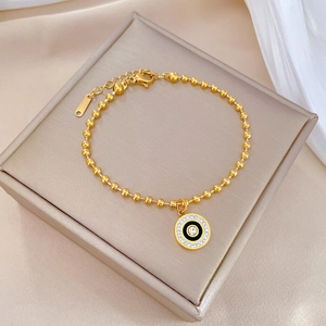 Detail of gold Roman circle bracelet with crystals and S.STEEL tag on white silk