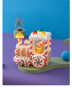 Close-up of lighted gingerbread man train ornament with candy wheels and warm internal glow
