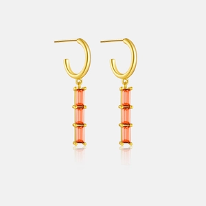Macro shot of gold drop earrings featuring four stacked rectangular orange zircons on white