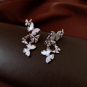 Détails de boucles d'oreilles pendantes argentées avec papillons en nacre et zircons