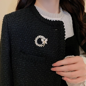 Détail d'une broche fleur dorée avec perles et zircon sur une veste en tweed