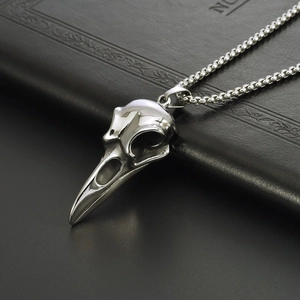Detailed close-up of a silver punk crow skull pendant made of polished titanium steel