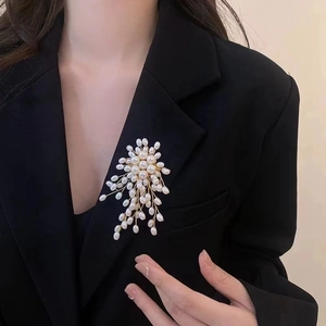 Detail of luxury pearl brooch with gold wire weaving on a black suit lapel