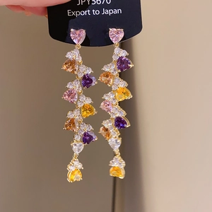 Detail of long tassel earrings with heart-shaped colorful zircons in gold-tone setting