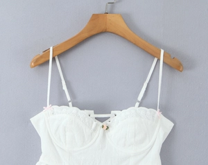 Detailed view of white lace trim neckline with pink flower accent and tie-up front design