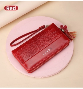 Detail of red crocodile textured long wallet with tassel zipper and wrist strap