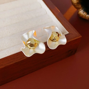 Detail of silver wavy earrings with gold faceted ball studs on a velvet tray