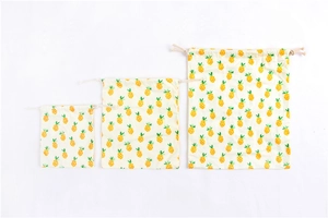 Three-piece set of cream cotton drawstring bags with yellow pineapple print in various sizes
