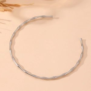 Detailed view of silver stainless steel bamboo style choker on a natural warm background