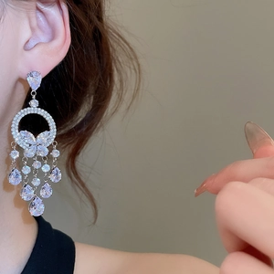 Vue détaillée des boucles d'oreilles papillon argentées avec pompons en strass sur mannequin