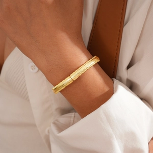 Detail of 18k gold plated bangle with vertical stripes on female model wrist