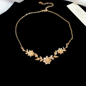 Macro view of gold flower and leaf pendant necklace with rhinestones on black velvet