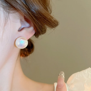 Detail of aurora pearl stud earrings on model showing elegant iridescent white luster