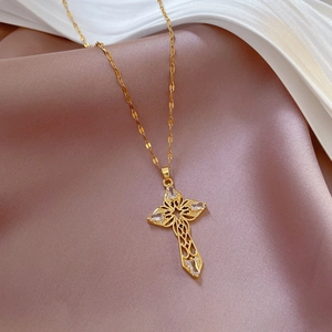 Close-up of gold hollow cross necklace with crystal inlays on elegant silk fabric