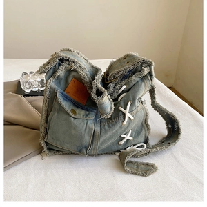 Detail of vintage washed denim bag featuring frayed edges and side lace-up strap design