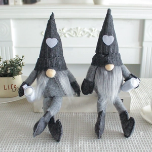 Pair of knitted grey Christmas gnomes with heart patches sitting in a cozy home setting