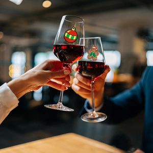 Christmas wine glass markers with PVC charms shown in a festive party toasting scene