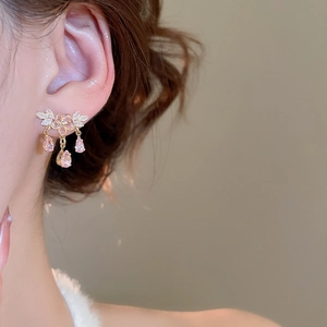 Dettaglio dell'orecchino a fiore rosa con nappa di zirconi e finitura dorata sul modello