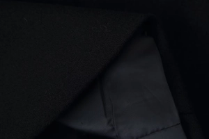 Close-up detail of black wool fabric texture and smooth inner lining of the coat