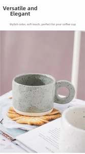Detail of a ceramic mug with ink splatter pattern and a unique circular handle design