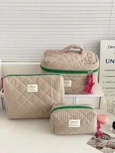 Detailed view of three quilted checkered pouches with contrast zippers and fringe