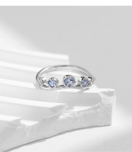 Detail of silver wave ring featuring five sparkling light blue and pink gemstones