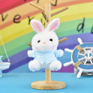 Detailed shot of a cute white plush bunny keychain wearing a light blue hoodie on a stand