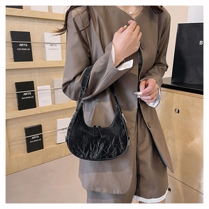 Detail of the black pleated texture and crescent shape on a stylish underarm bag
