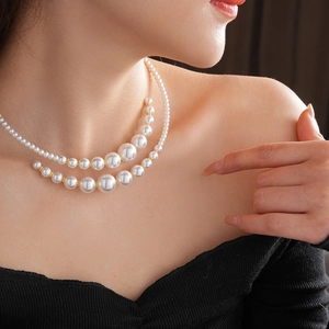 Elegant double-layered white pearl choker necklace with gold bead accents on a female model