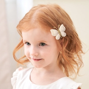 Handmade crochet butterfly hair clip on a young girl in a soft beige setting