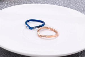 Macro de bagues en forme de V or rose et bleu avec cristaux sertis sur assiette blanche