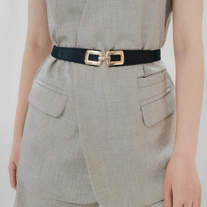 Close-up of black elastic dress belt with double rectangular interlocking gold buckle