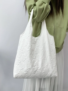 Close-up of white 3D floral embossed fabric on a large capacity tote shopping bag