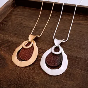 Vintage gold and silver hollow teardrop necklaces with woven leather texture on wood