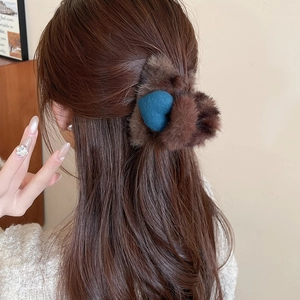 Détail d'une pince à cheveux en peluche marron avec cœur bleu portée de dos