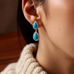 Detail of vintage silver needle drop earrings with turquoise stones and zircons worn by model