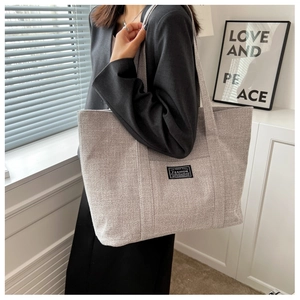Detail of grey woven tote bag with fashion label shown in natural minimalist lighting